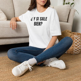 Mujer sentada en un sofá con la camiseta blanca ¿Y SI SALE BIEN? de Idea Mala Club