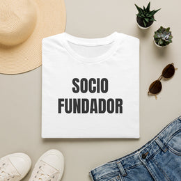 Camiseta blanca SOCIO FUNDADOR doblada junto a unos vaqueros, gafas de sol y un sombrero de paja