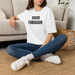 Mujer sentada en un sofá con la camiseta blanca SOCIO FUNDADOR de Idea Mala Club