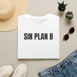 Camiseta blanca SIN PLAN B doblada junto a unos vaqueros, gafas de sol y un sombrero de paja
